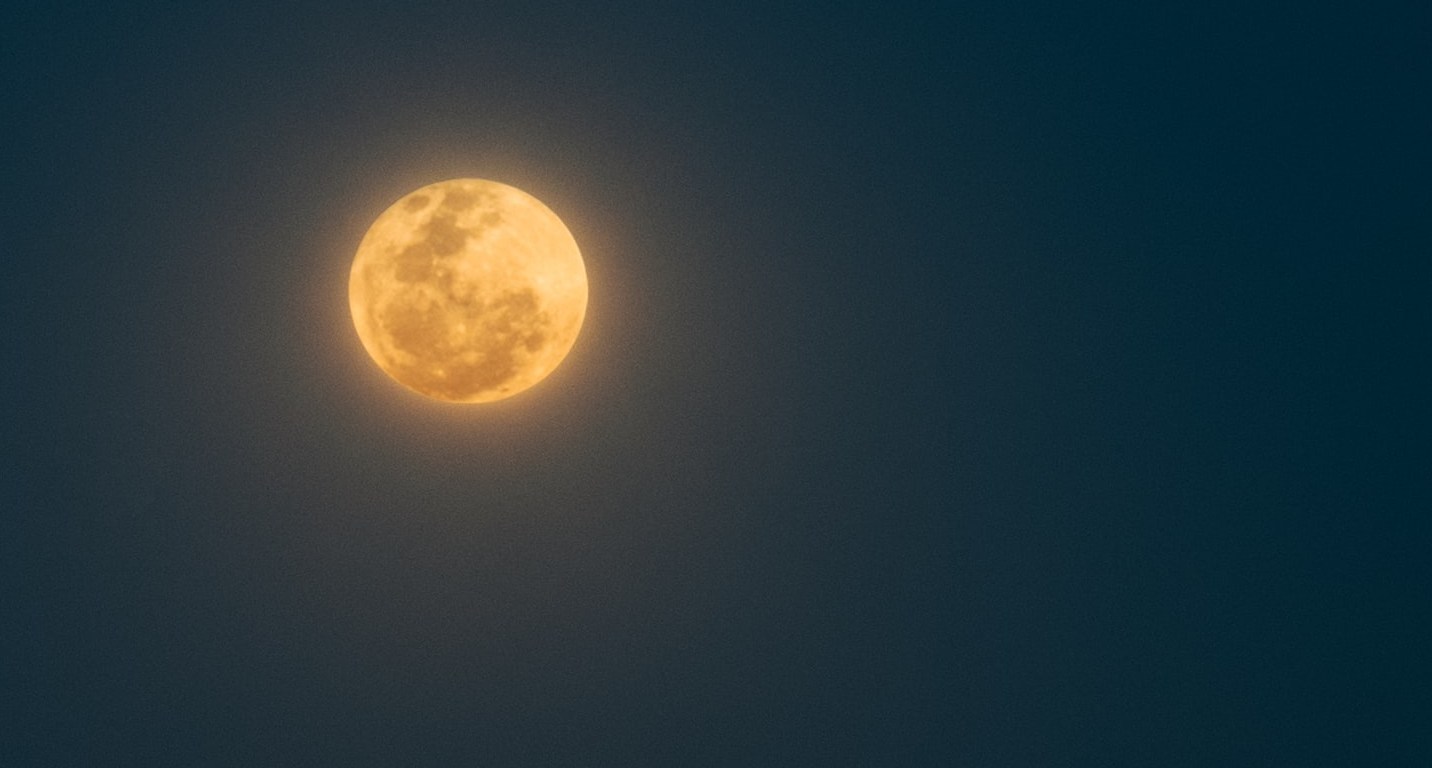 Full orange-colored moon glowing in a dark sky