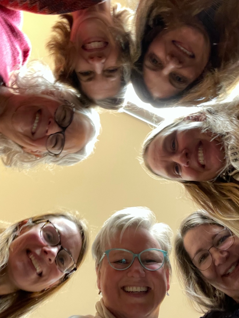 Seven smiling women looking down at the camera
