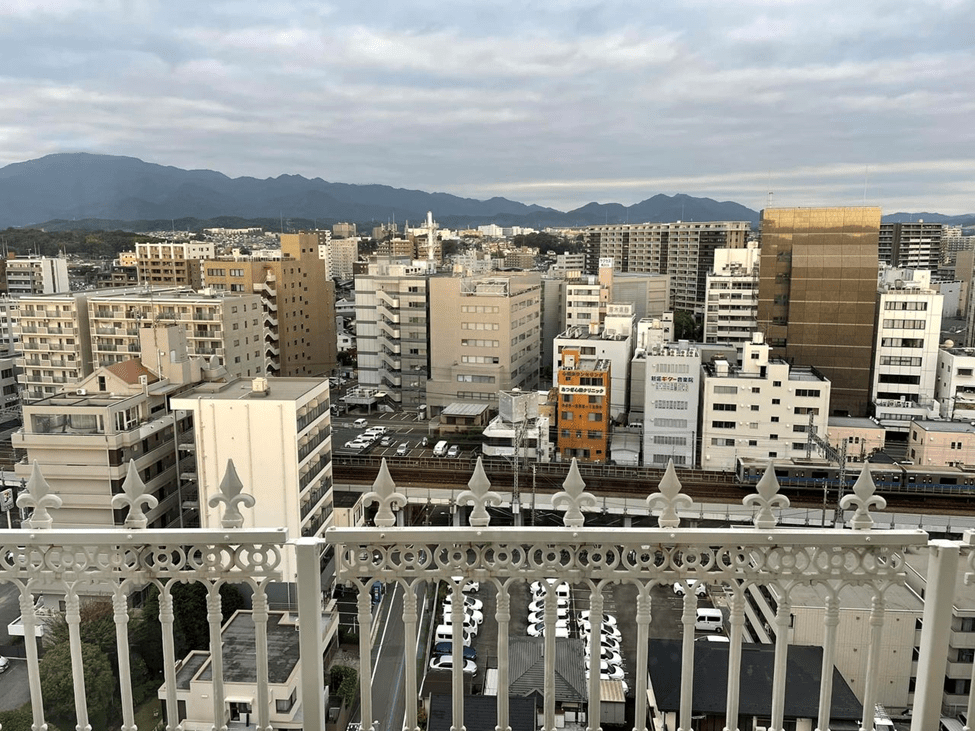 A city scene from above -- tall buildings, parking lots and a train running through -- and low mountains in the distance